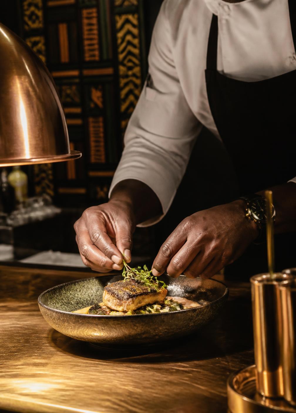 Chef Amara Laurent finishing a plate at the Lumière pass